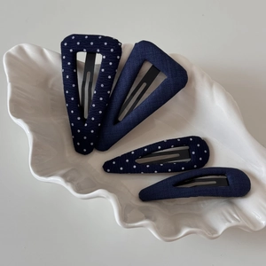 Navy blue polka dot hair clips set on a white shell plate for elegant side styling