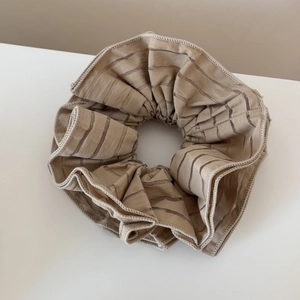 Close-up of beige mesh scrunchie featuring elegant brown stripe patterns and soft texture