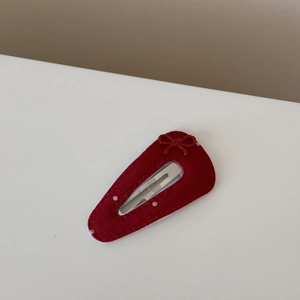 Détail de la barrette en velours rouge avec nœud à pois et fermoir en métal argenté