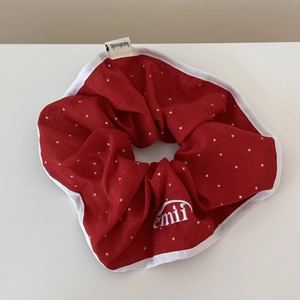 Détail d'un chouchou rouge à pois blancs avec étiquette faite main et logo brodé