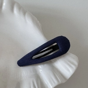 Detailed view of dark blue polka dot fabric BB hair clip on a white shell tray