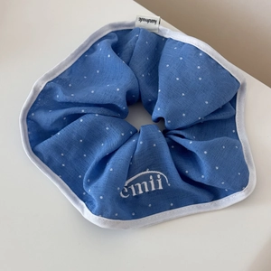 Gros plan sur le chouchou bleu à pois avec étiquette artisanale et broderie blanche