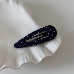 Detail of navy blue polka dot hair clip on white decorative shell tray accessory