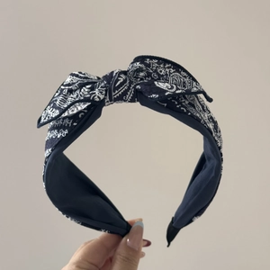 Detail of navy blue paisley pattern scrunchie with delicate lace edges and top bow