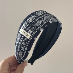 Detail view of navy paisley headband with delicate lace trim and brand woven label