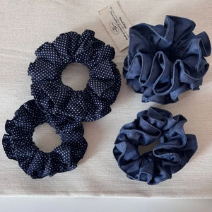 Détail de quatre chouchous en denim bleu et à pois sur un support textile naturel
