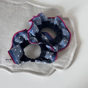 Detailed macro view of two blue polka dot mesh hair scrunchies with red trimmed edges