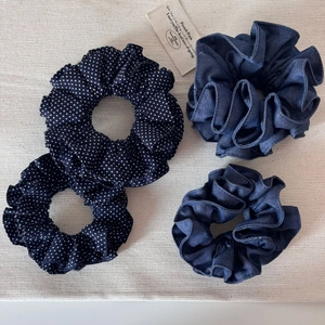 Détail de quatre chouchous en denim bleu uni et à pois sur un fond texturé beige