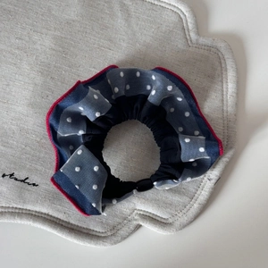 Close-up of blue polka dot mesh scrunchie with red stitching and layered fabric texture