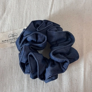 Détail d'un chouchou en denim bleu foncé montrant la texture du tissu et les coutures fines