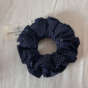 Détail du chouchou bleu foncé à pois avec texture en tissu plissé et design élastique