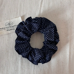 Détail du chouchou bleu marine à pois blancs avec texture froissée et bande élastique