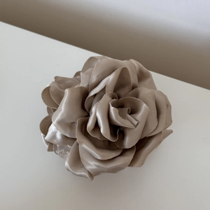 Gros plan détaillé d'une pince à cheveux rose en satin champagne avec une texture de soie