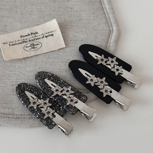 Detail of four acetate hair clips with sparkling stars and fine silver glitter finish