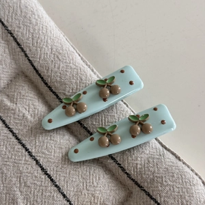 Gros plan sur des barrettes bleu clair avec motifs cerises 3D et pois marrons mignons