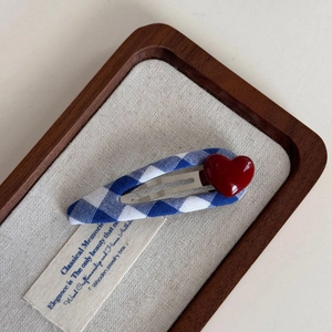 Detail of blue and white gingham fabric snap clip with a glossy red heart decoration