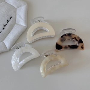 Detail view of four D-shaped acetate hair claws in leopard, marble, and amber patterns