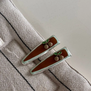 Détail des barrettes à cheveux cerise rétro avec finition en résine verte et marron