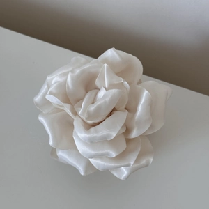 Gros plan d'une pince à cheveux rose en satin blanc crème avec pétales élégants