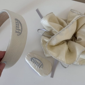Détail d'un ensemble de chouchous et bandeau crème avec bordure argentée brodée