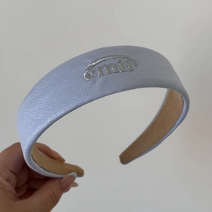 Détail du serre-tête en tissu bleu clair avec broderie emii argentée élégante