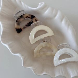 Set of four tortoise shell acetate hair claws in crescent shapes on a white tray