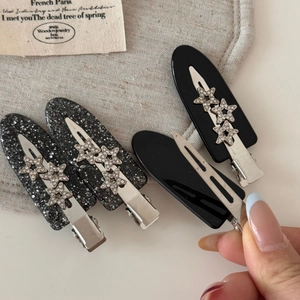 Detailed close-up of glittering black acetate hair clips with silver star rhinestones