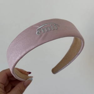 Détail d'un serre-tête en satin rose avec broderie argentée et rembourrage en éponge