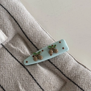 Détail d'une pince à cheveux bleu clair rectangulaire avec motifs cerises marron