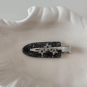 Detail of a black acetate star hair clip with sparkling rhinestones on a white plate