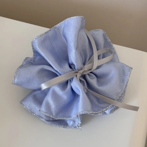 Détail d'un chouchou en soie bleu-violet avec bords argentés et texture plissée élégante