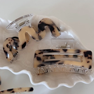 Close-up of leopard pattern cellulose acetate hair claws on a decorative shell tray
