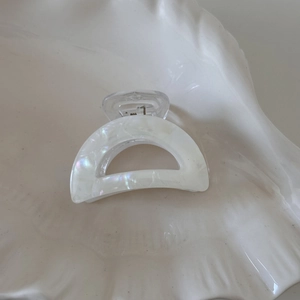 Macro shot of iridescent pearl white acetate hair claw clip on ceramic plate