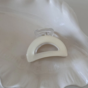 Macro shot of cream-colored claw clip with transparent handle on shell tray