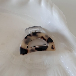 Detail view of acetate leopard print hair claw clip on a white ceramic wavy tray