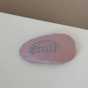 Détail d'un chouchou rose en tissu avec broderie emmi argentée et texture brillante