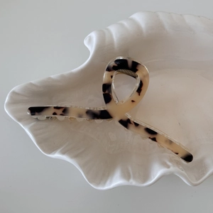 Detail view of tortoiseshell acetate shark hair claw clip on shell-shaped tray