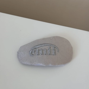Gros plan d'un chouchou en tissu gris avec broderie argentée et texture satinée