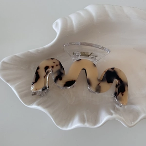 Detail view of cream leopard print acetate hair claw clip with elegant wave design