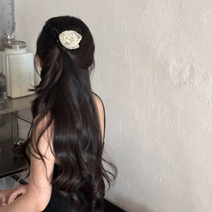Elegant off-white rose hair claw clip in lace fabric shown on a model's wavy long hair