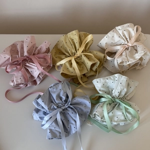 Close-up of five colorful polka dot drawstring bags with satin ribbon and ruffle edges