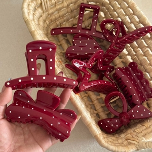 Detail view of burgundy hair claw clips with white polka dots in various unique shapes
