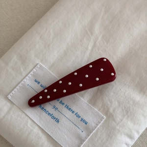 Nahaufnahme einer burgunderroten Polka-Dot-Haarspange auf weißem Leinenstoff
