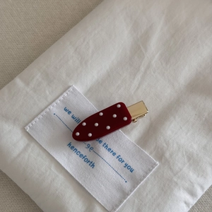 Nahaufnahme einer roten Polka-Dot-Haarklammer auf Stoff mit goldener Metallbasis