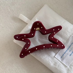 Close-up of star-shaped burgundy hair claw clip with white polka dots and gold spring