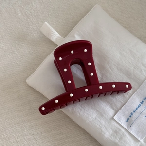 Macro shot of dark red burgundy hair claw clip with white polka dots on fabric