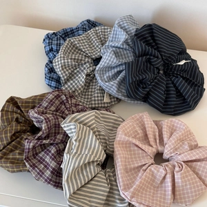 Close-up of various plaid and striped fabric scrunchies in sea salt blue and soft tones