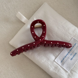 Close-up of a burgundy polka dot hair claw clip with a strong metallic gold spring