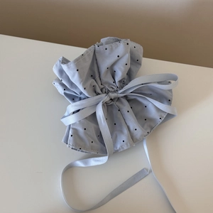 Detail of light blue polka dot drawstring bag with a silky satin ribbon bow tie