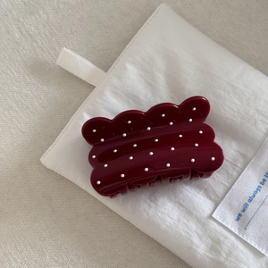 Detailed macro view of burgundy hair claw clip with white polka dots and scalloped edges